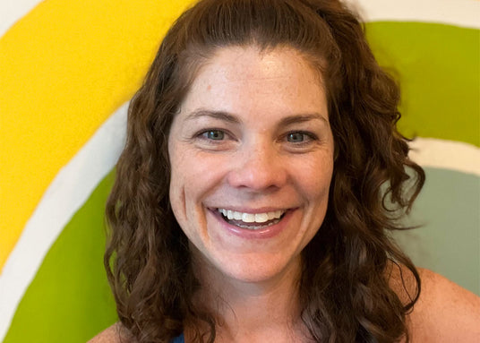 Woman with curly hair smiling in front of a colorful background