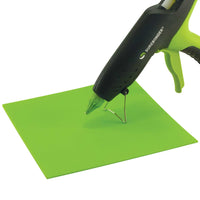 Hot glue gun hovers over a green Surebonder silicone pad, measures 8 inches by 8 inches