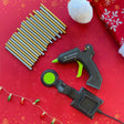Hot glue gun and accessories on a red background with Christmas decorations.