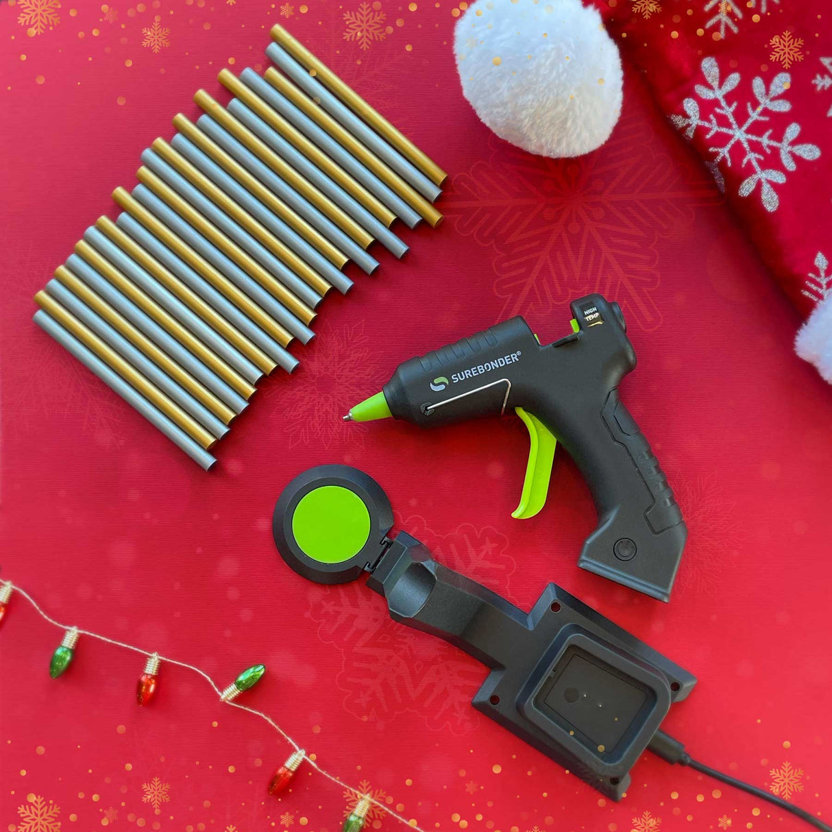 Hot glue gun and accessories on a red background with Christmas decorations.